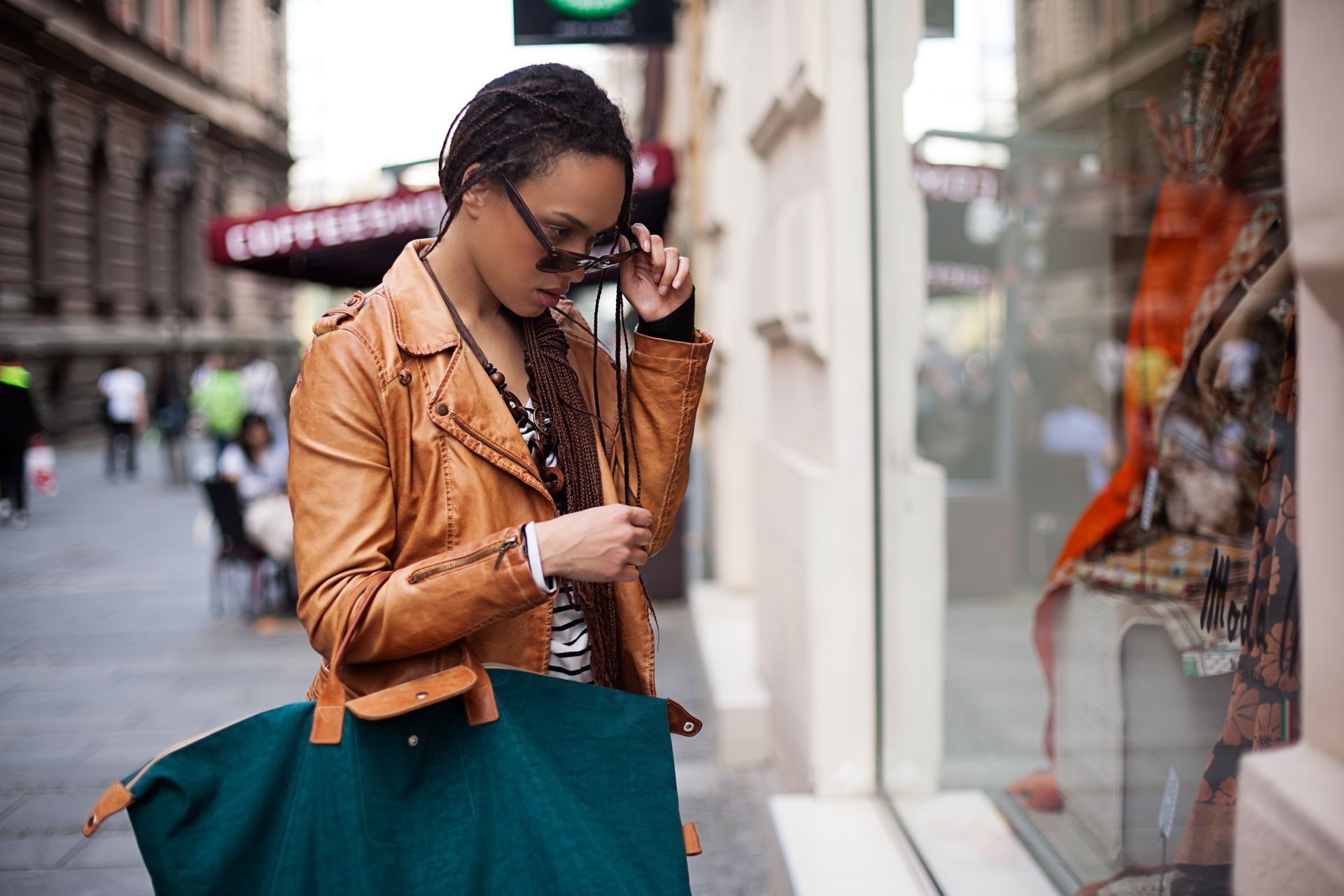 A woman is standing in front of a store window looking at her phone.