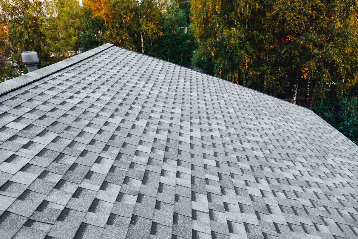 A roof with a lot of shingles on it is surrounded by trees