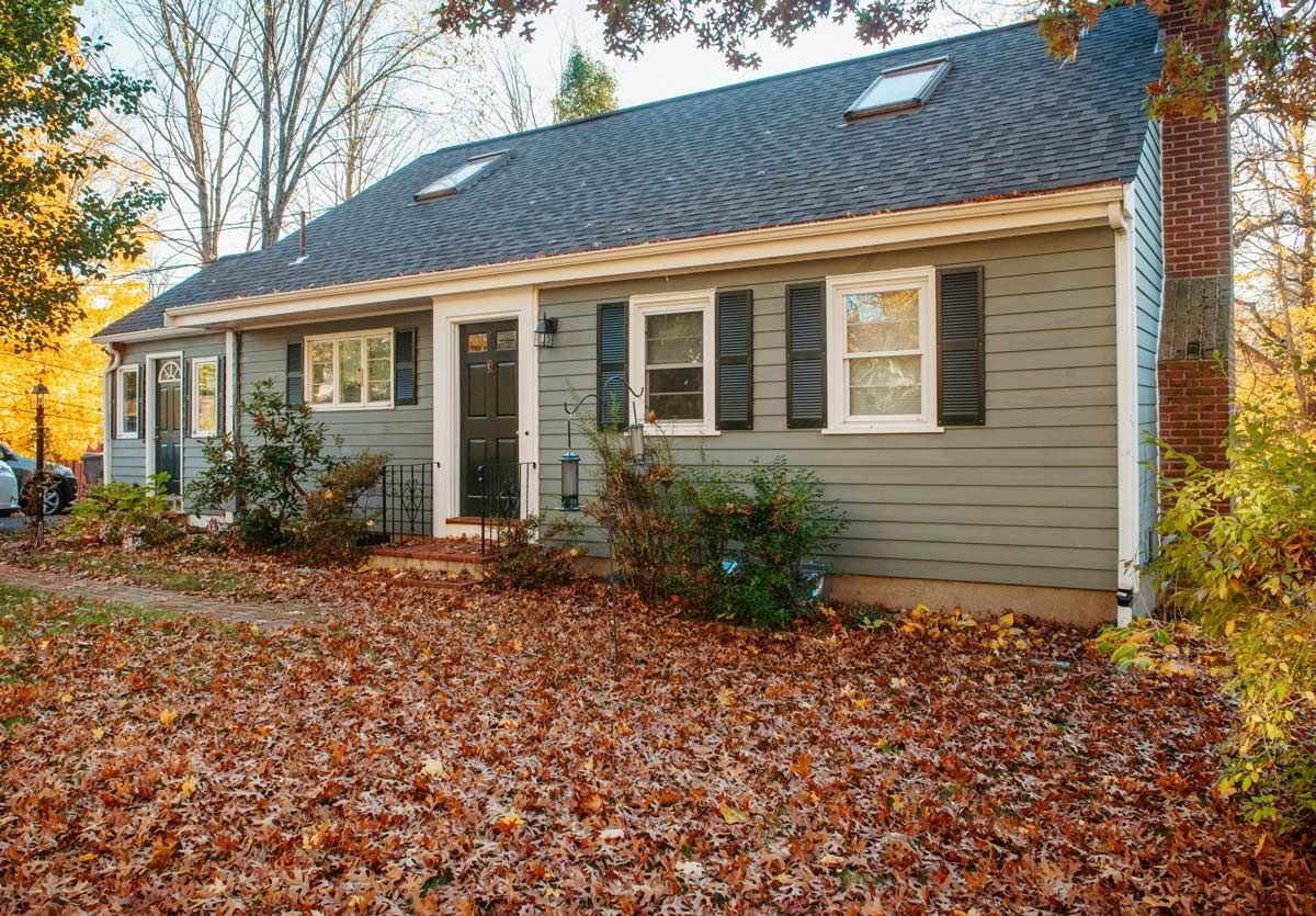 A house with a lot of leaves on the ground in front of it