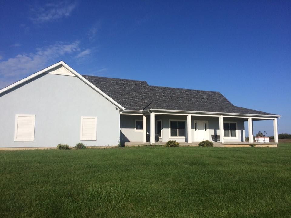 A house with a porch and a blue sky in the background
