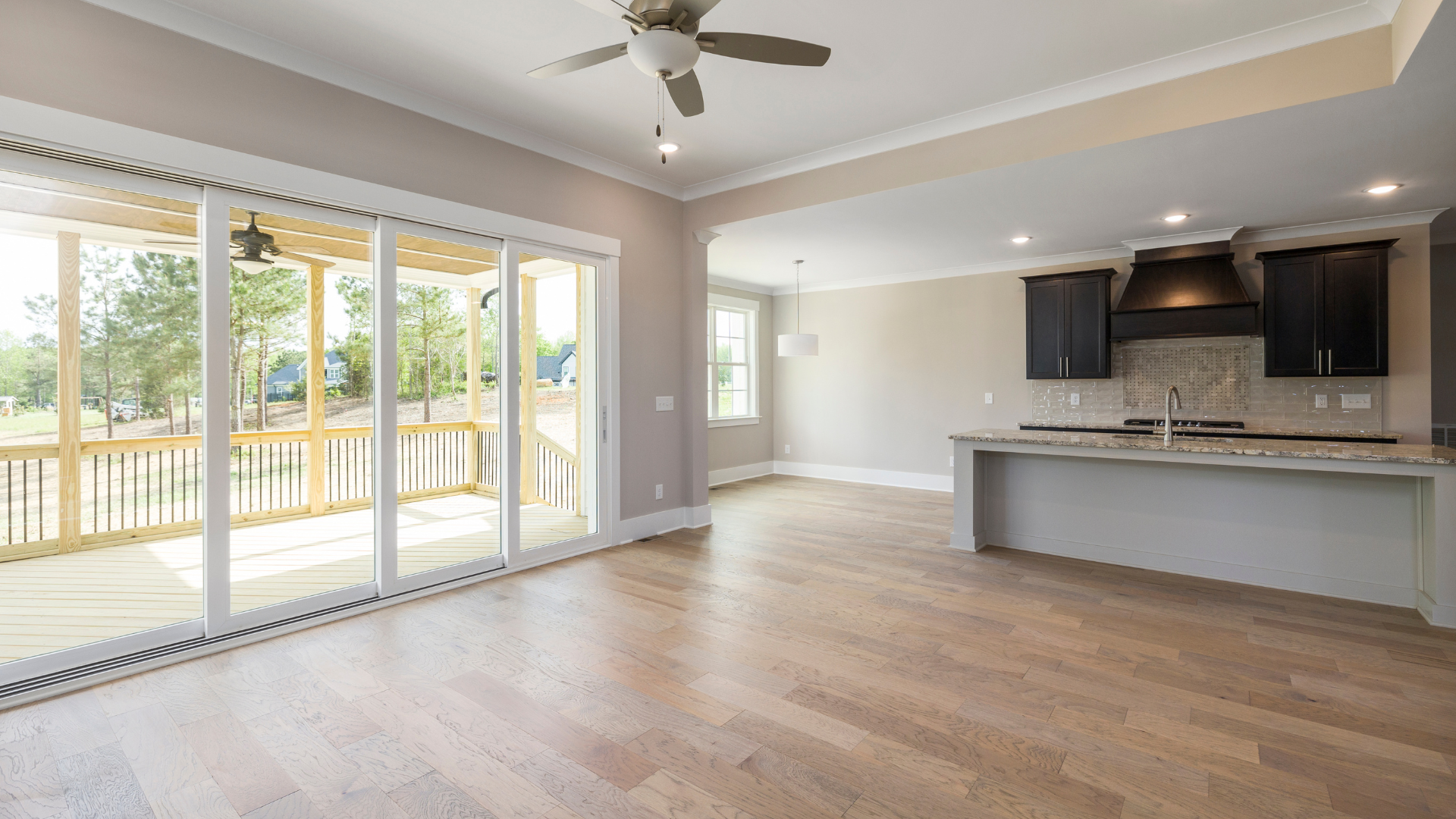 Open-concept kitchen and living room with sliding glass doors leading to a porch. Light-colored hardwood floors.