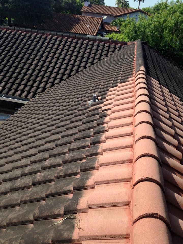 The roof of a house is being cleaned and painted