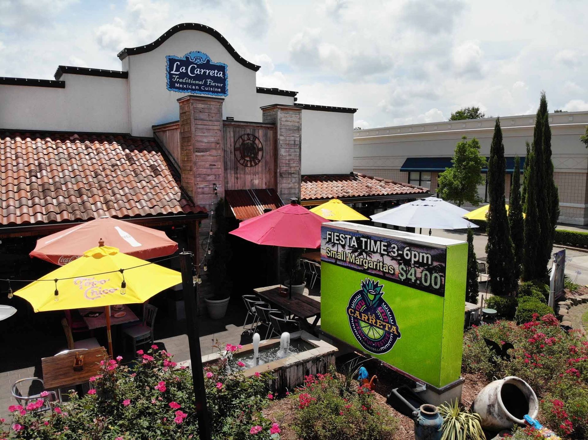 Exterior of La Carreta Mexican Restaurant with outdoor seating, colorful umbrellas, and a sign.
