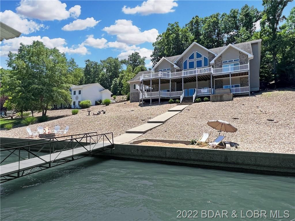 A large house is sitting on top of a hill next to a body of water.