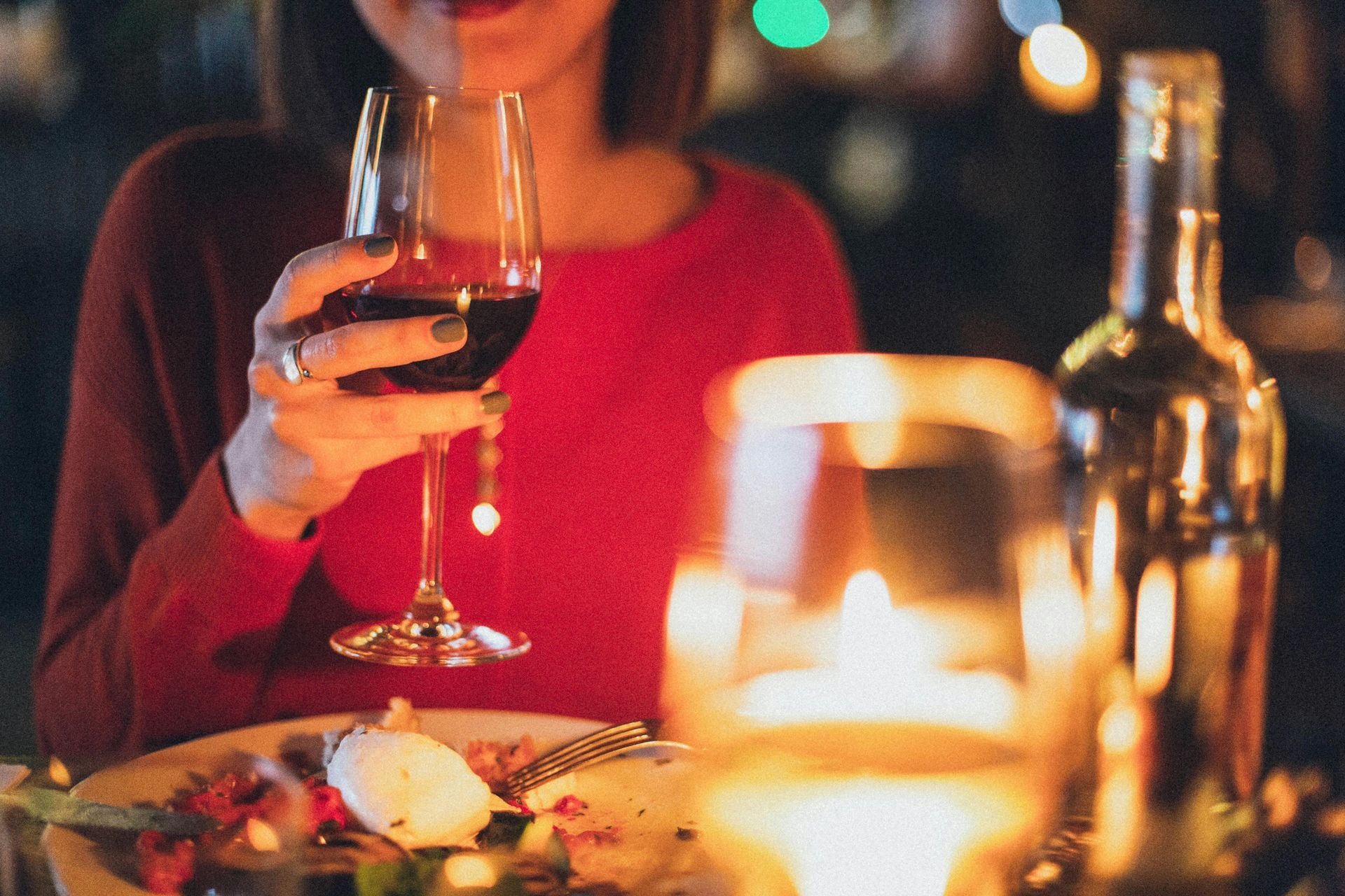 A woman is sitting at a table holding a glass of wine.