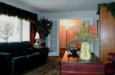 Cozy living room with black sofa, large window, wooden coffee table, and floral centerpiece