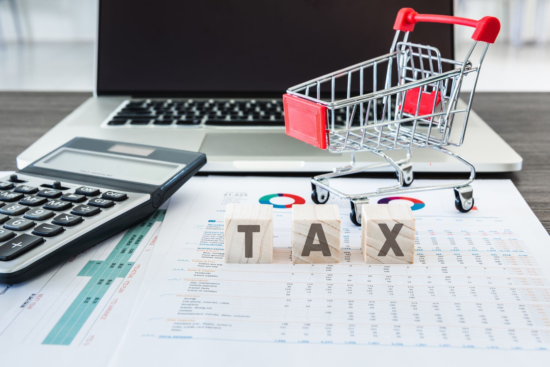 A shopping cart is sitting on a table next to a laptop and a calculator