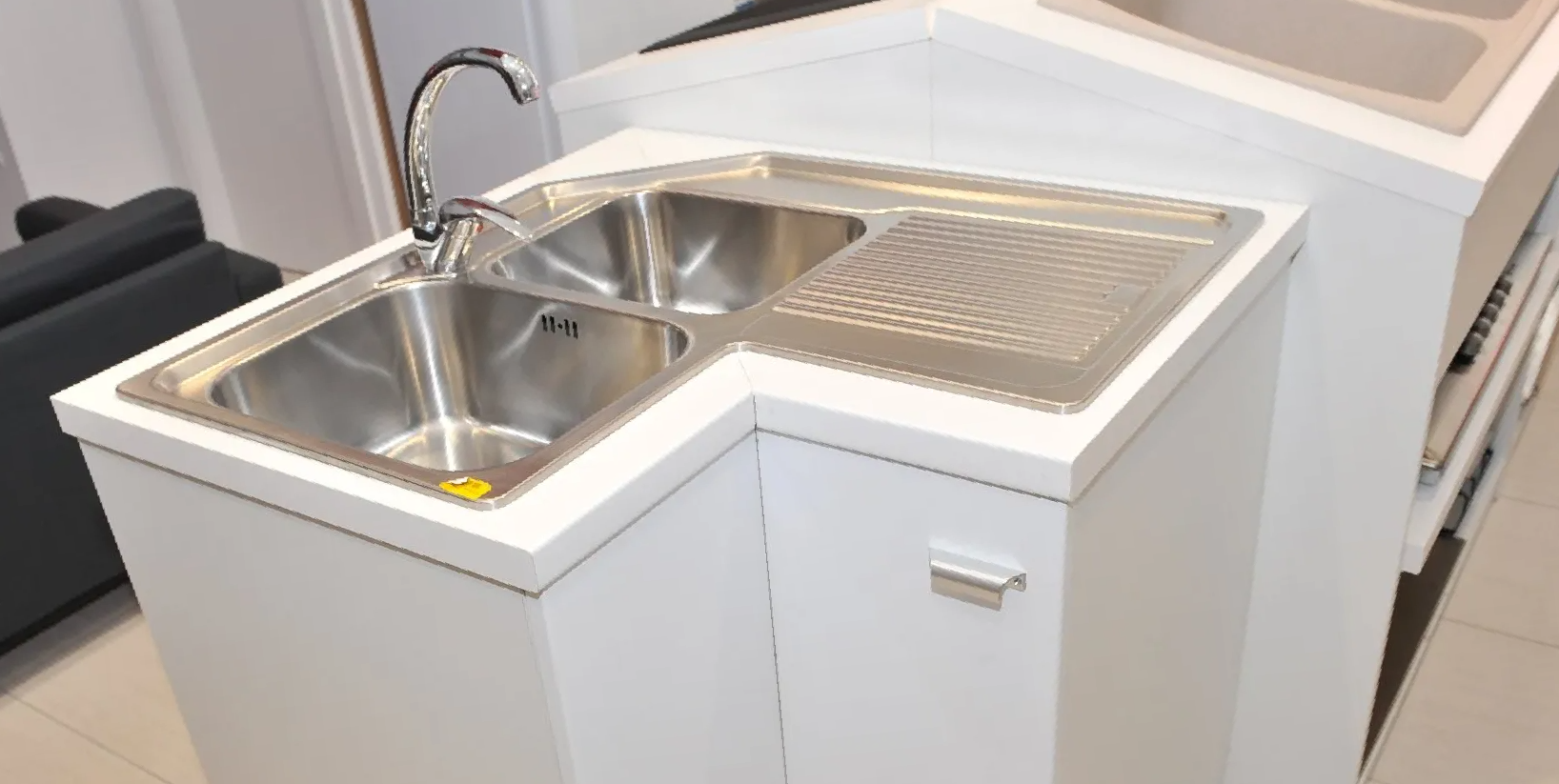Un'isola cucina angolare con lavello a doppia vasca in acciaio inox e scolapiatti integrato.
