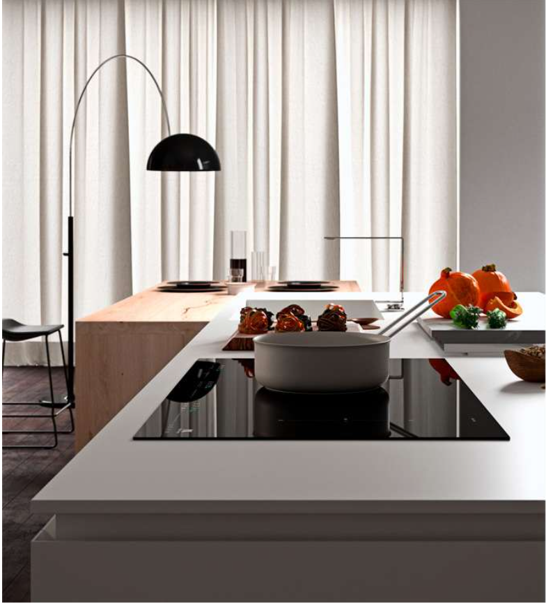 Una cucina moderna con piano di lavoro bianco, piano cottura a induzione nero, pentola e zucche decorative.