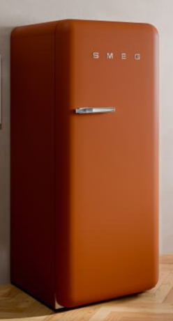 Un frigorifero SMEG in stile retrò color ruggine con maniglia cromata, appoggiato su un pavimento in legno contro una parete neutra.