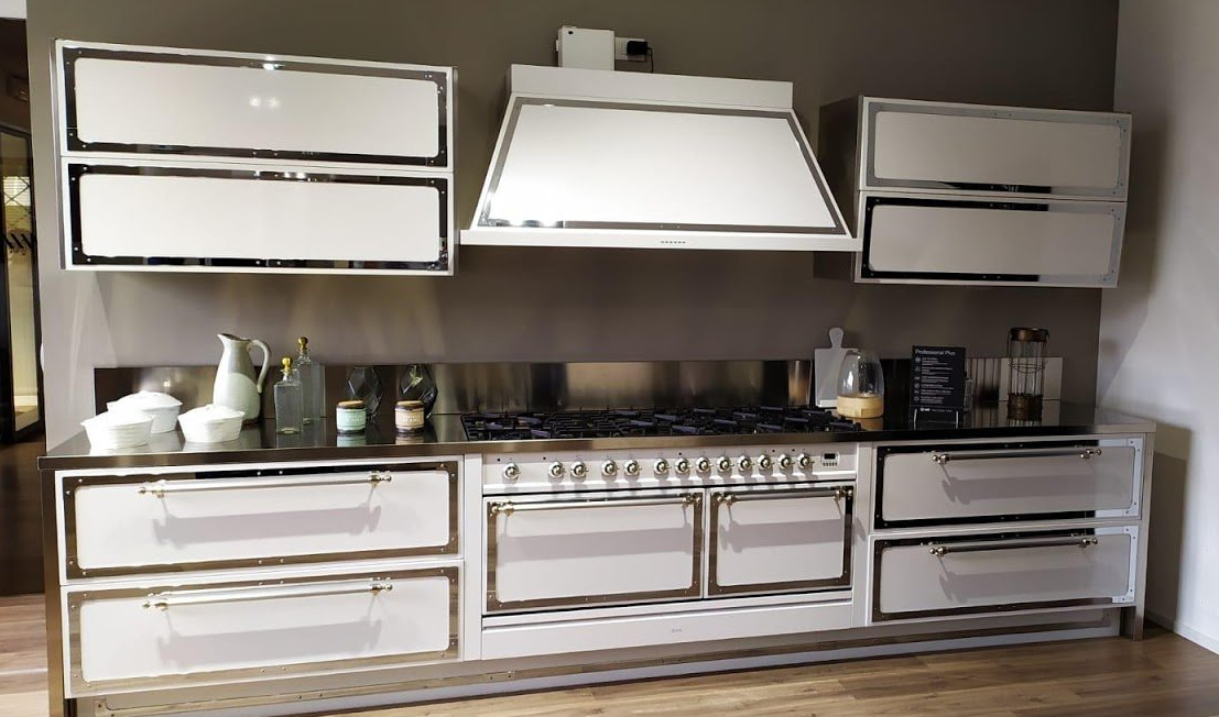 Una cucina moderna con mobili bianchi con cornici scure, un grande piano cottura in acciaio inox e una cappa abbinata.