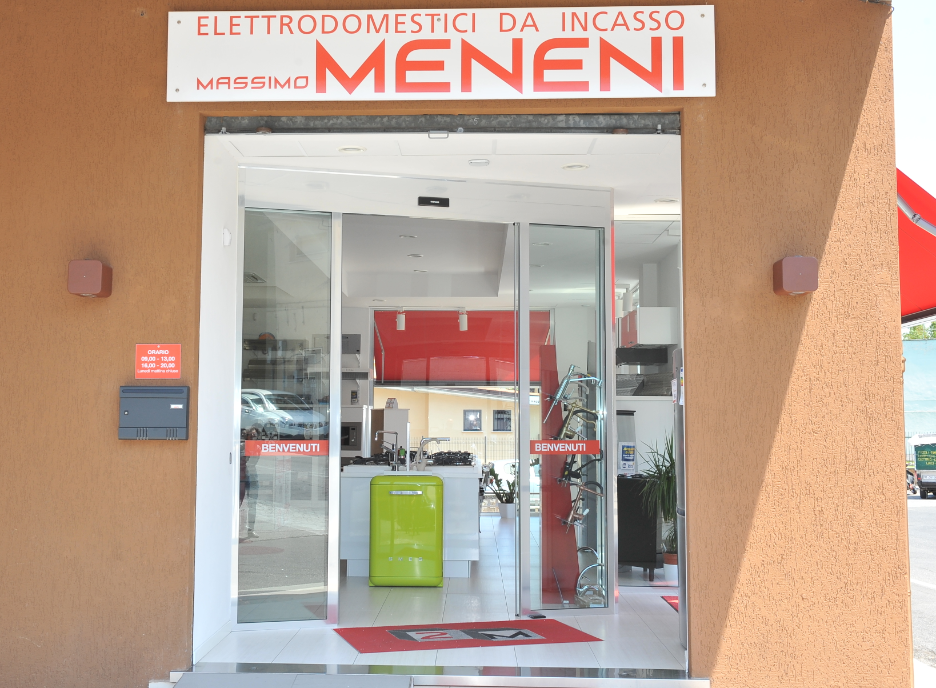 La vetrina del negozio di elettrodomestici di Massimo Meneni, con ingresso in vetro, insegne e allestimenti interni.