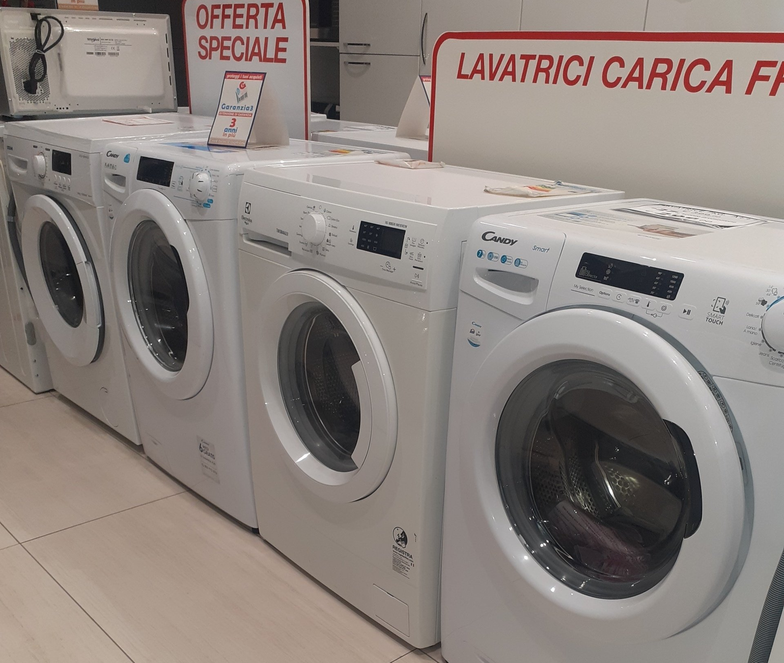 Una fila di lavatrici bianche a carica frontale esposte in vendita in un negozio.