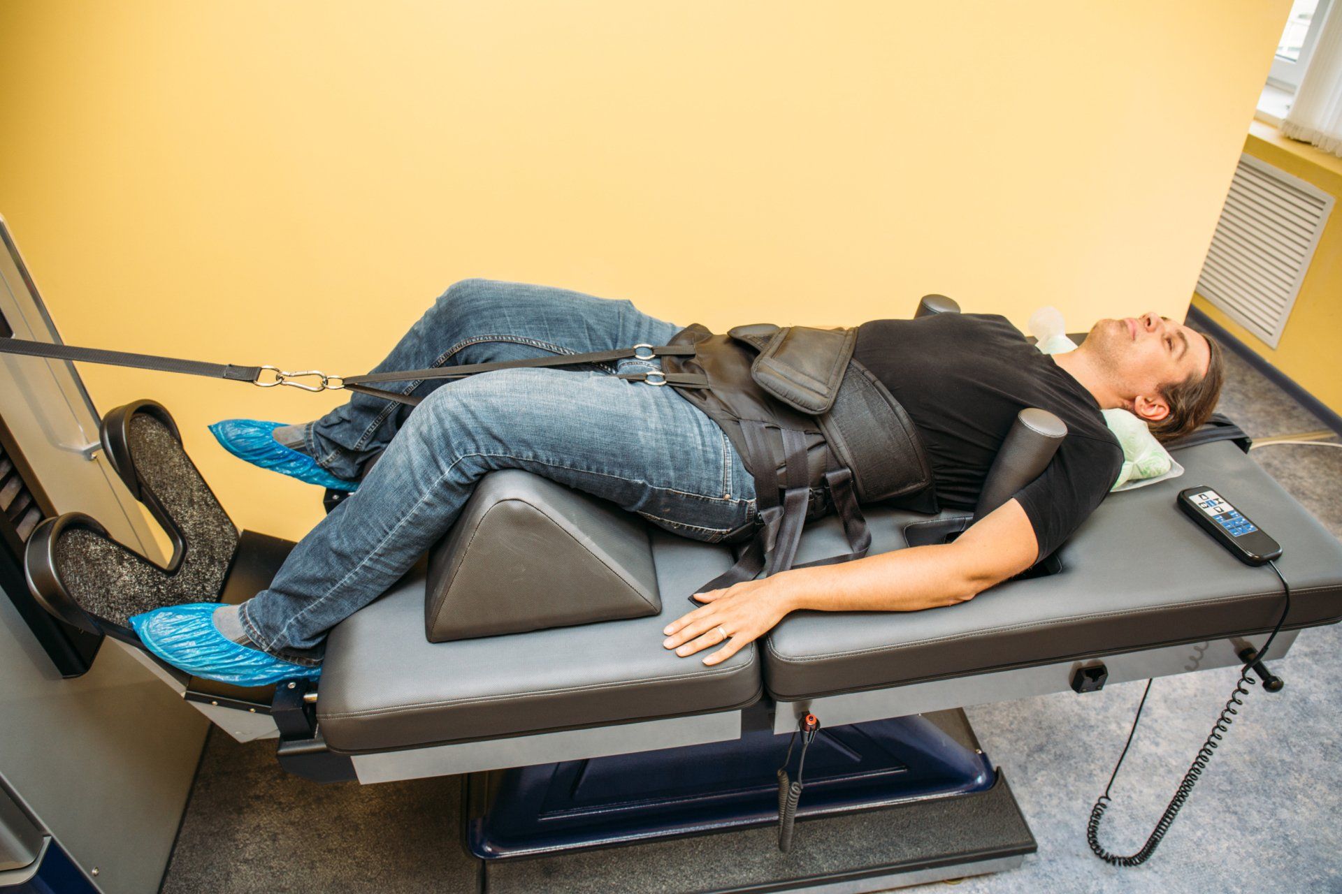 Man in jeans and black shirt on spinal decompression table.