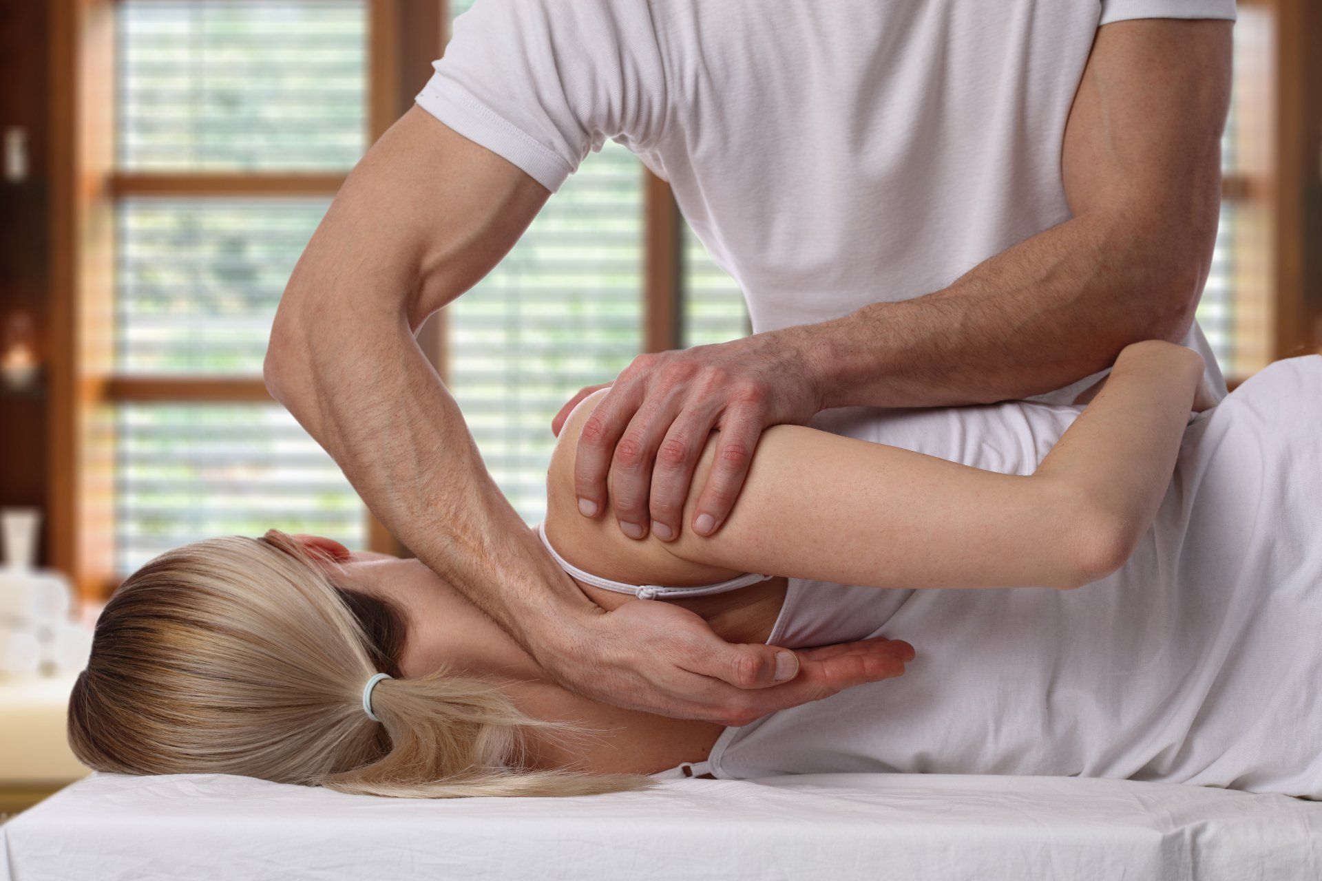 Person receiving shoulder massage from a masseuse; indoor setting.