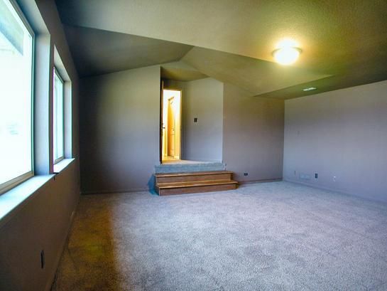 A large empty room with a lot of windows and carpet.