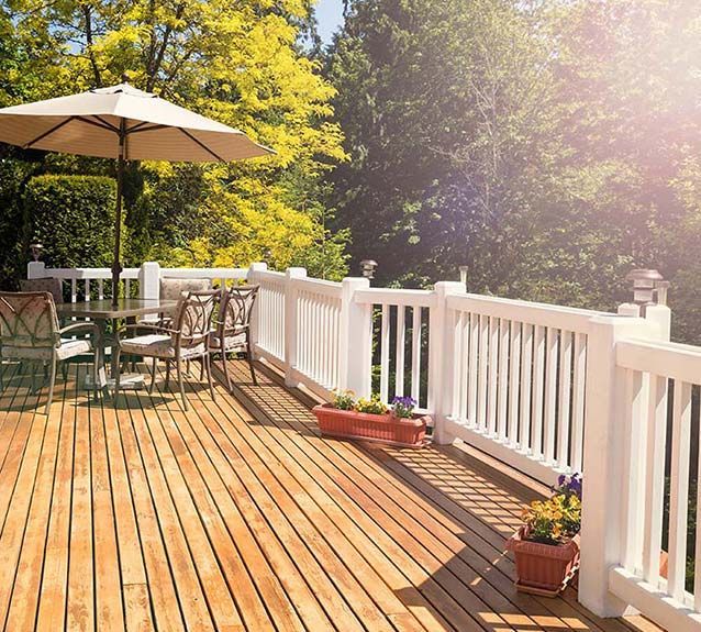 A wooden deck with a table and chairs and an umbrella