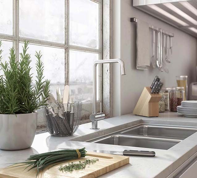 A kitchen with two sinks , a cutting board , and a potted plant.