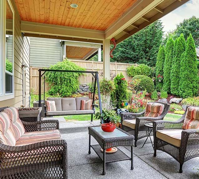 There is a porch with wicker furniture and a swing.
