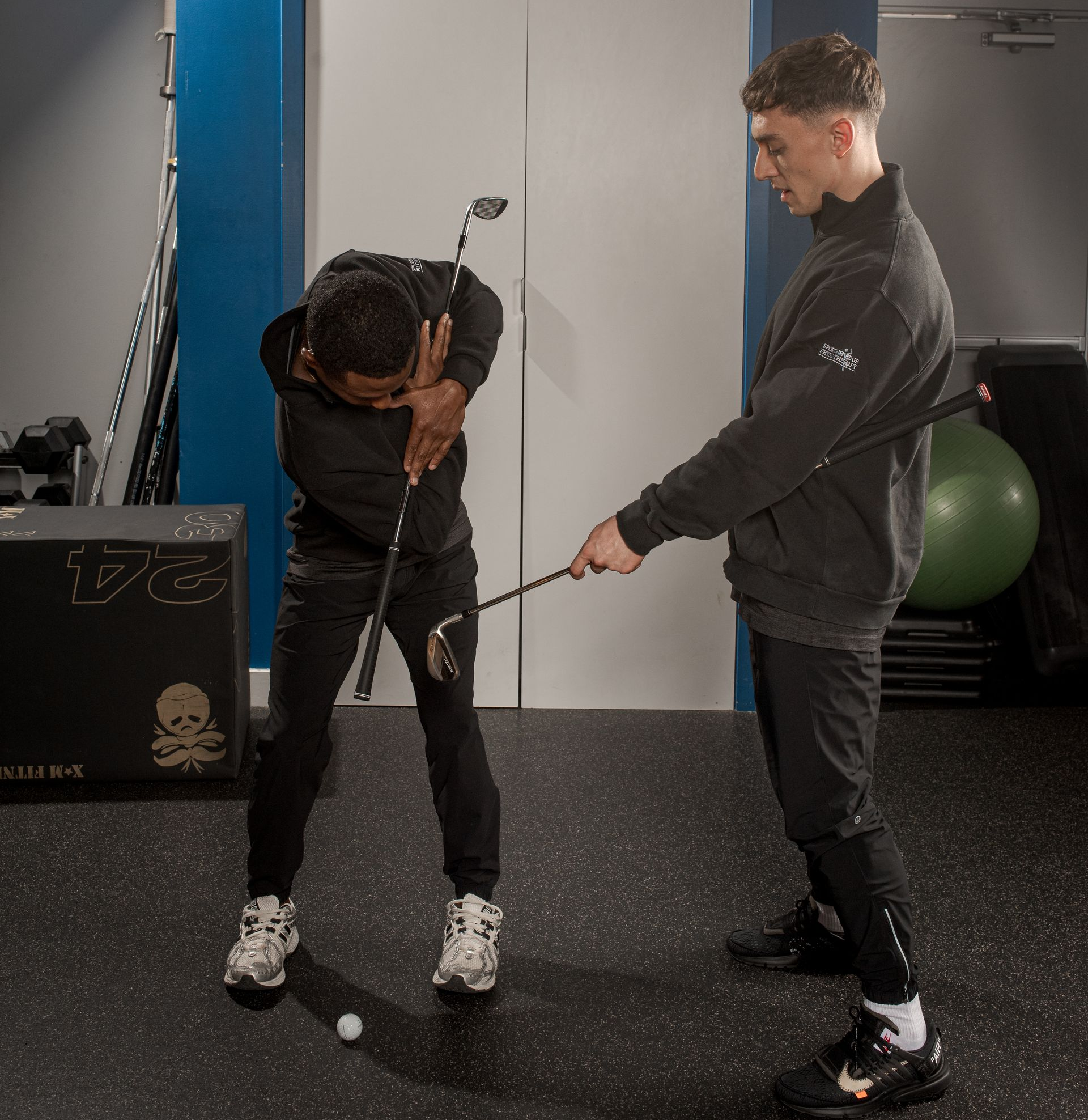 A person holding a golf club receives swing guidance from another individual in a room labeled Physiotherapy.