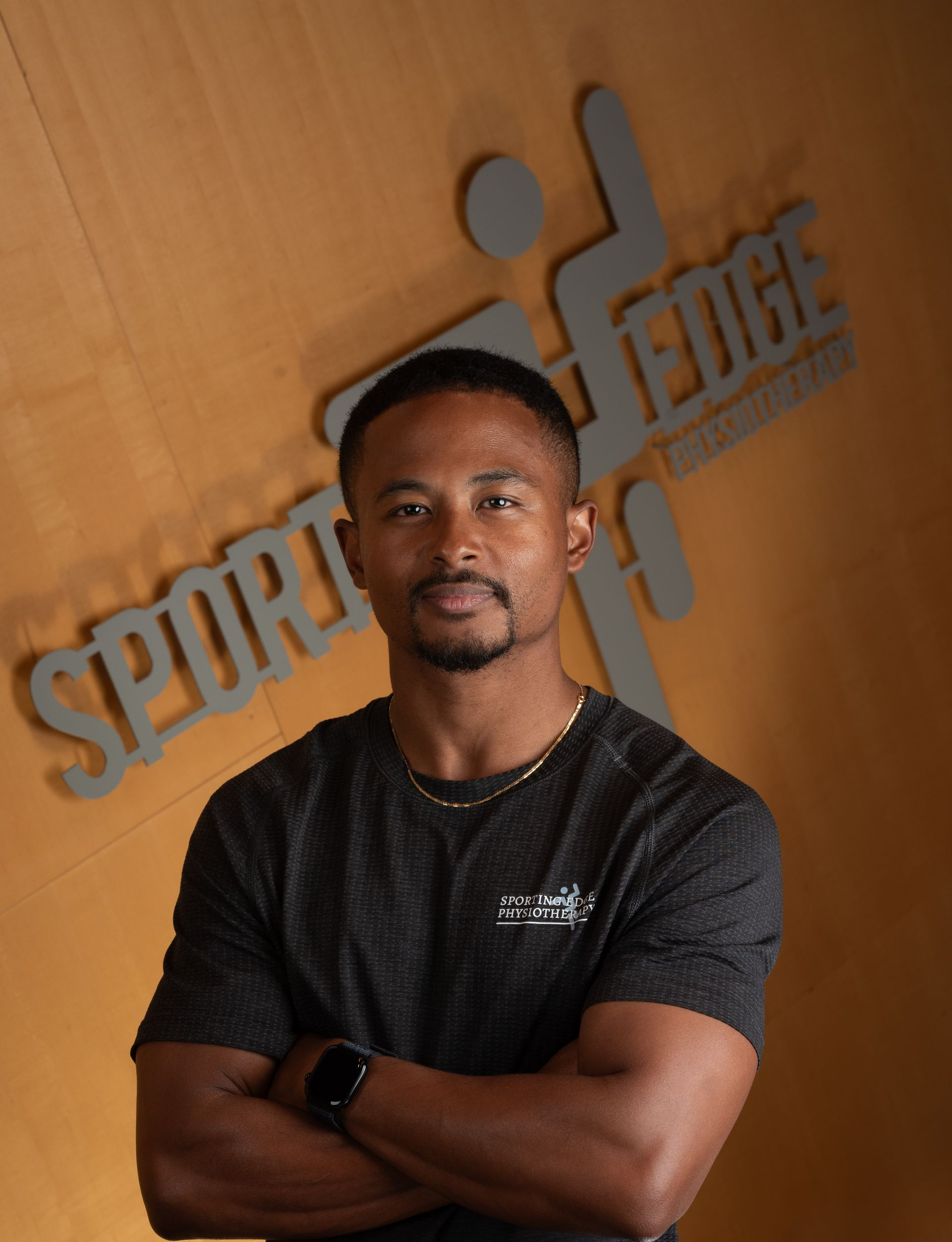Bentzen Takyi A person with short dark hair and a beard stands with arms crossed against a wood-paneled wall with a grey Sporting Edge logo.