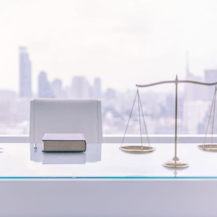 A glass desk with a book and scales of justice on it.