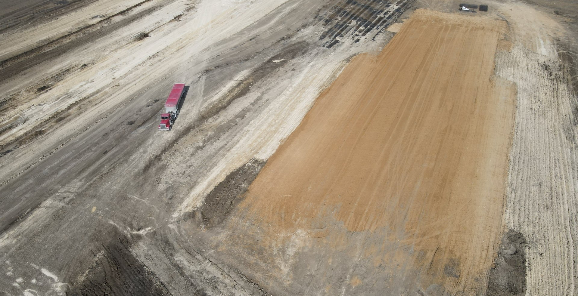 An aerial view of a truck driving down a dirt road.