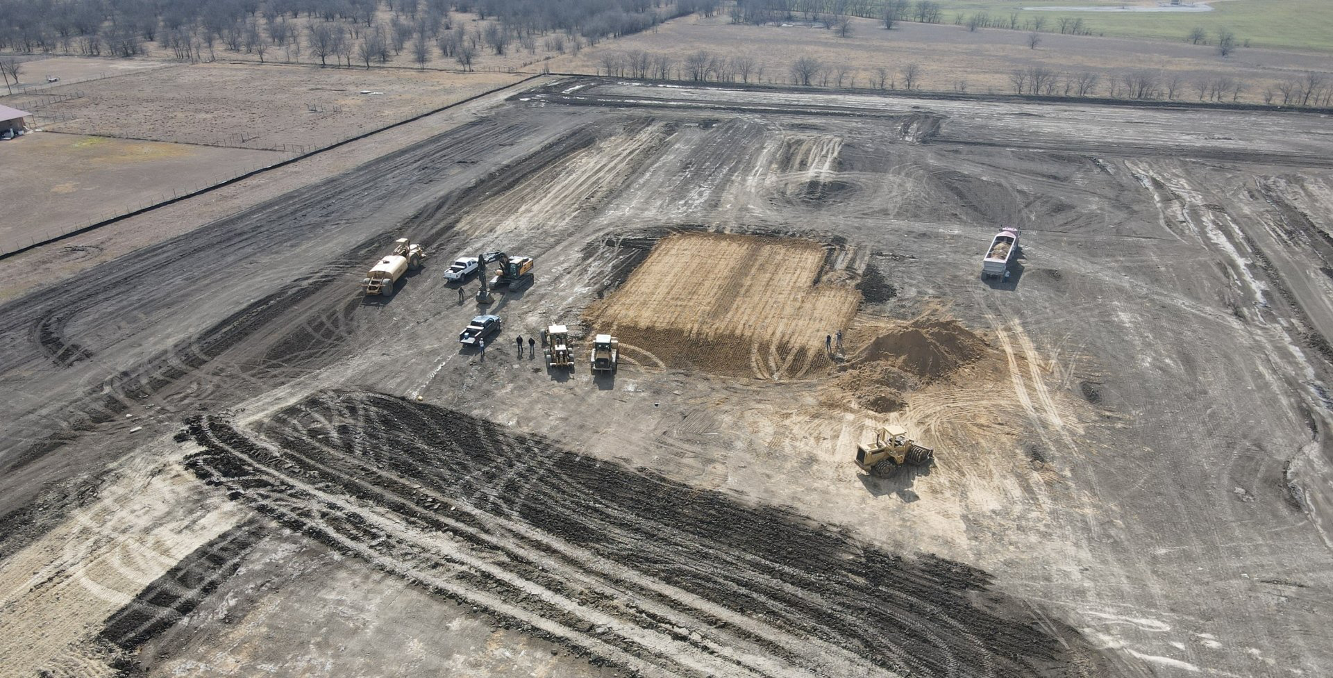 An aerial view of a construction site with trucks and tractors.