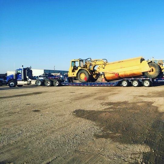 A yellow bulldozer is being transported on a flatbed trailer