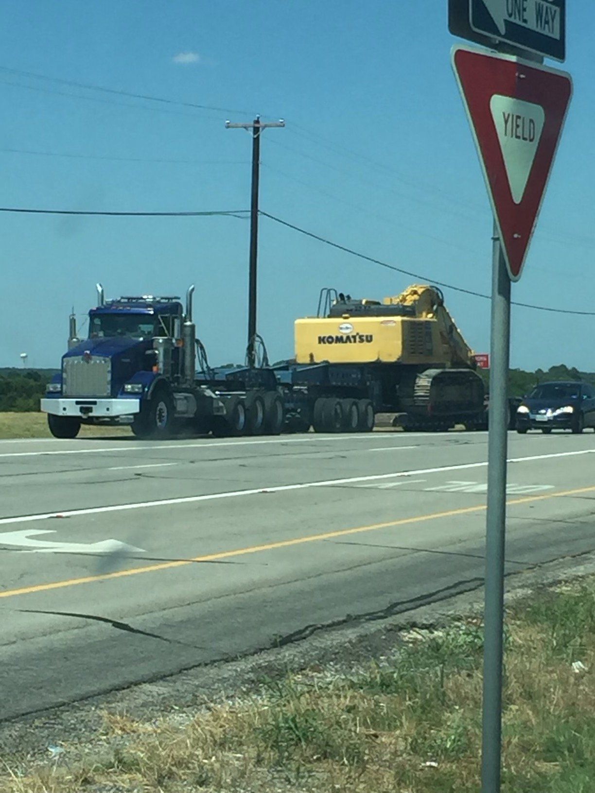 A blue truck is driving down a highway next to a sign that says yes