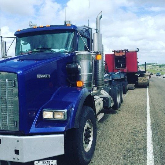 A blue kenworth semi truck is parked on the side of the road