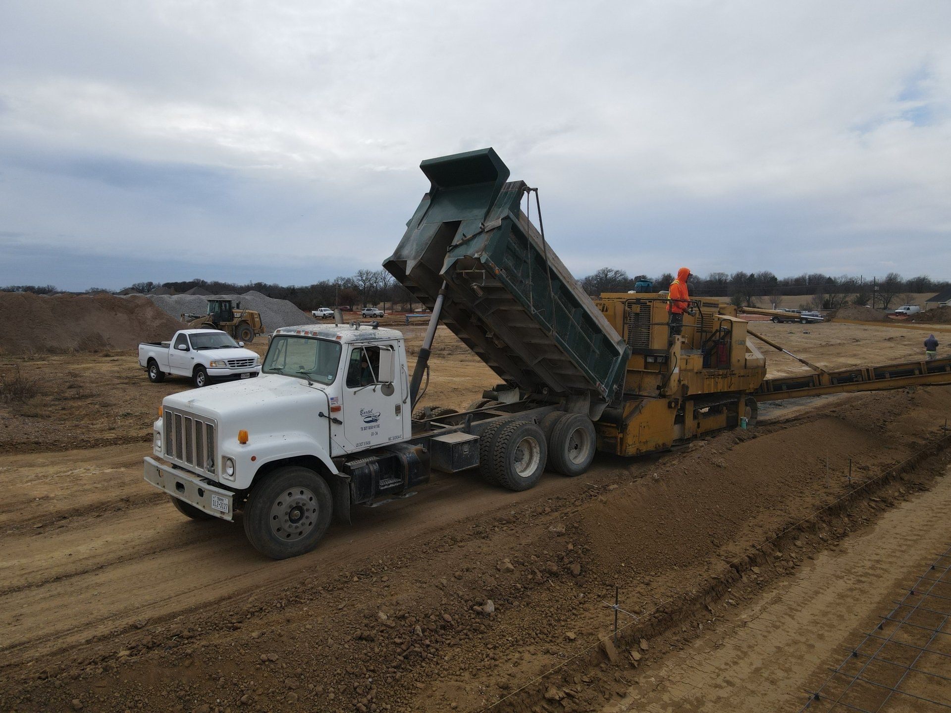 A dump truck is driving down a dirt road