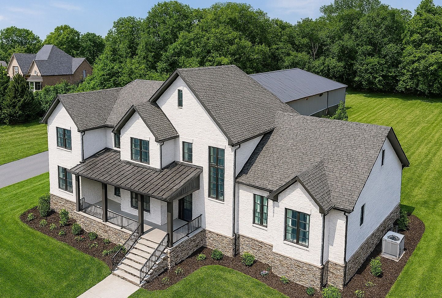 Aerial view of a large white house with gray roof, front porch, and surrounding green lawn and trees at redwood roofing and exteriors