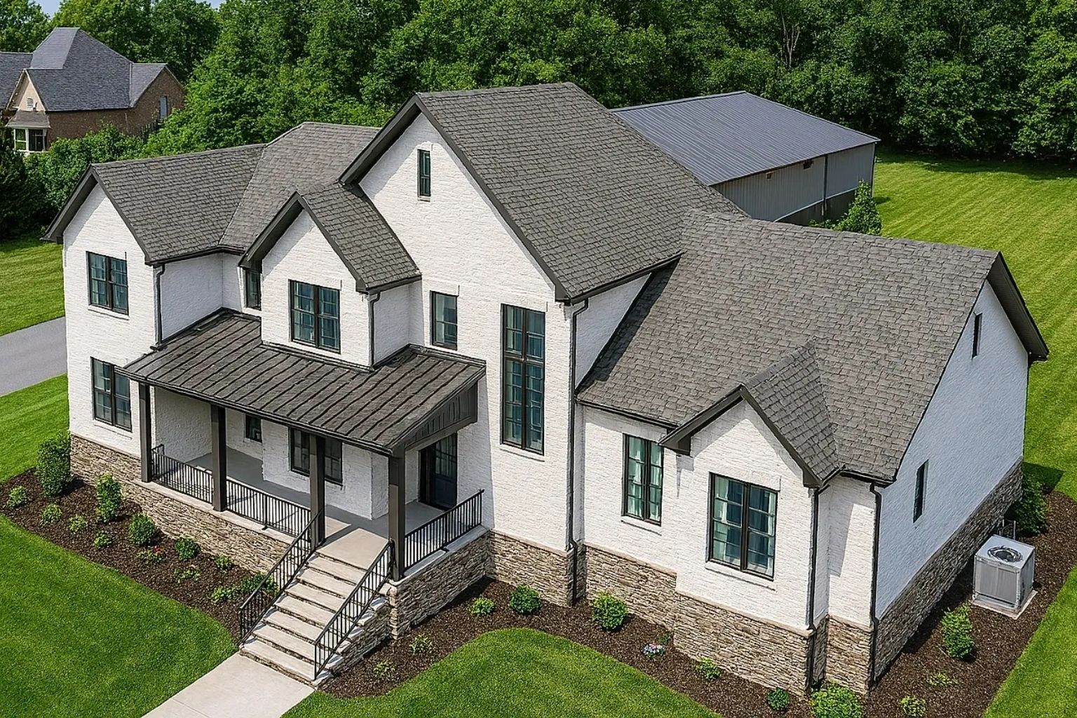 Aerial view of a white two-story house with gray roof, green shutters, and a front porch surrounded by trees at redwood roofing and exteriors