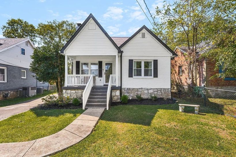 Small white bungalow with front porch, steps, and walkway in a grassy yard under a clear sky at redwood roofing in Tennessee 