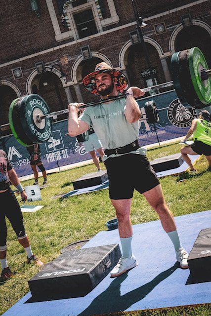 A man in a cowboy hat is squatting with a barbell.