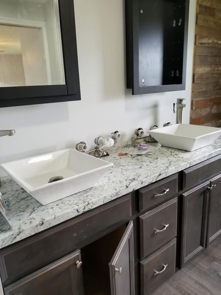 A double vanity with white vessel sinks, granite countertops, and dark wooden cabinets in a modern bathroom.