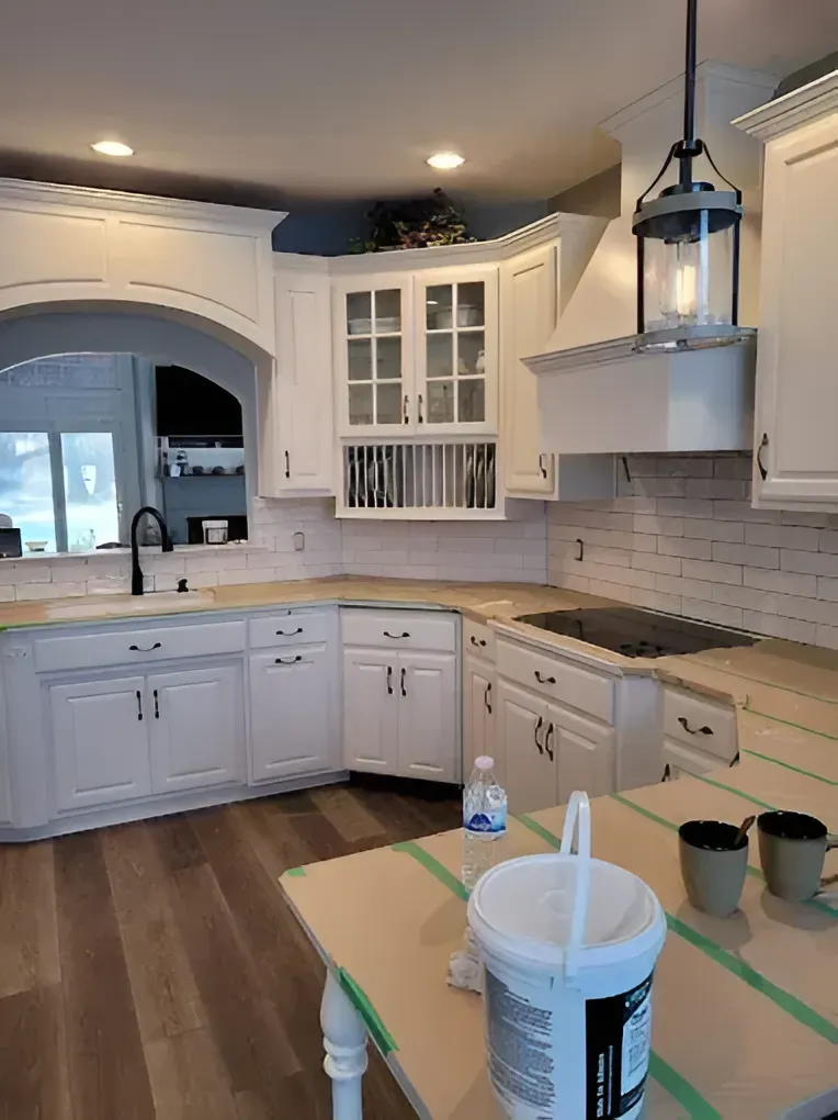 A kitchen remodel featuring white cabinets, a farmhouse sink, subway tile backsplash, and a pendant light over the counter.