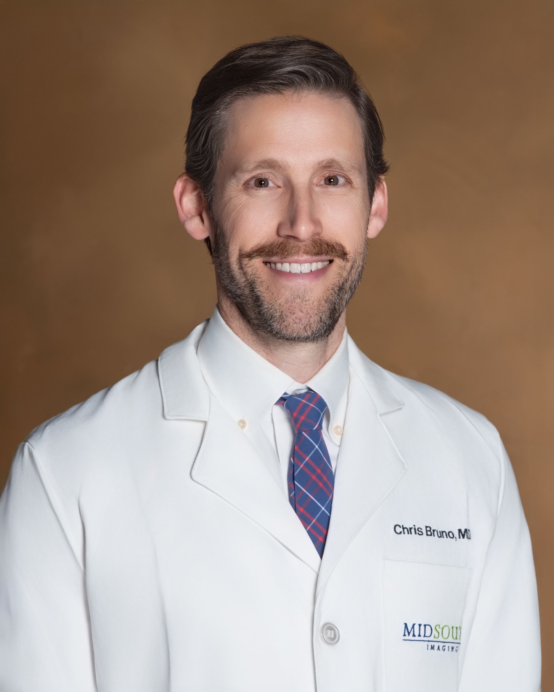 A man in a white coat and tie is smiling for the camera.