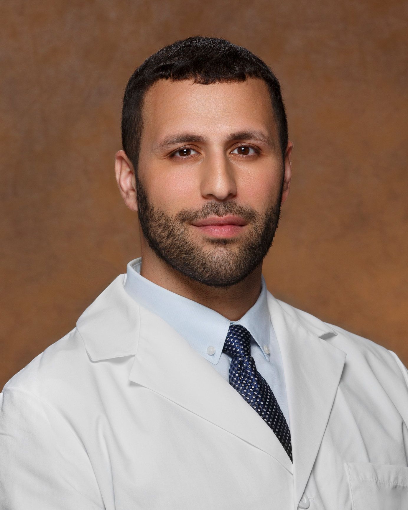 A man with a beard wearing a white coat and tie