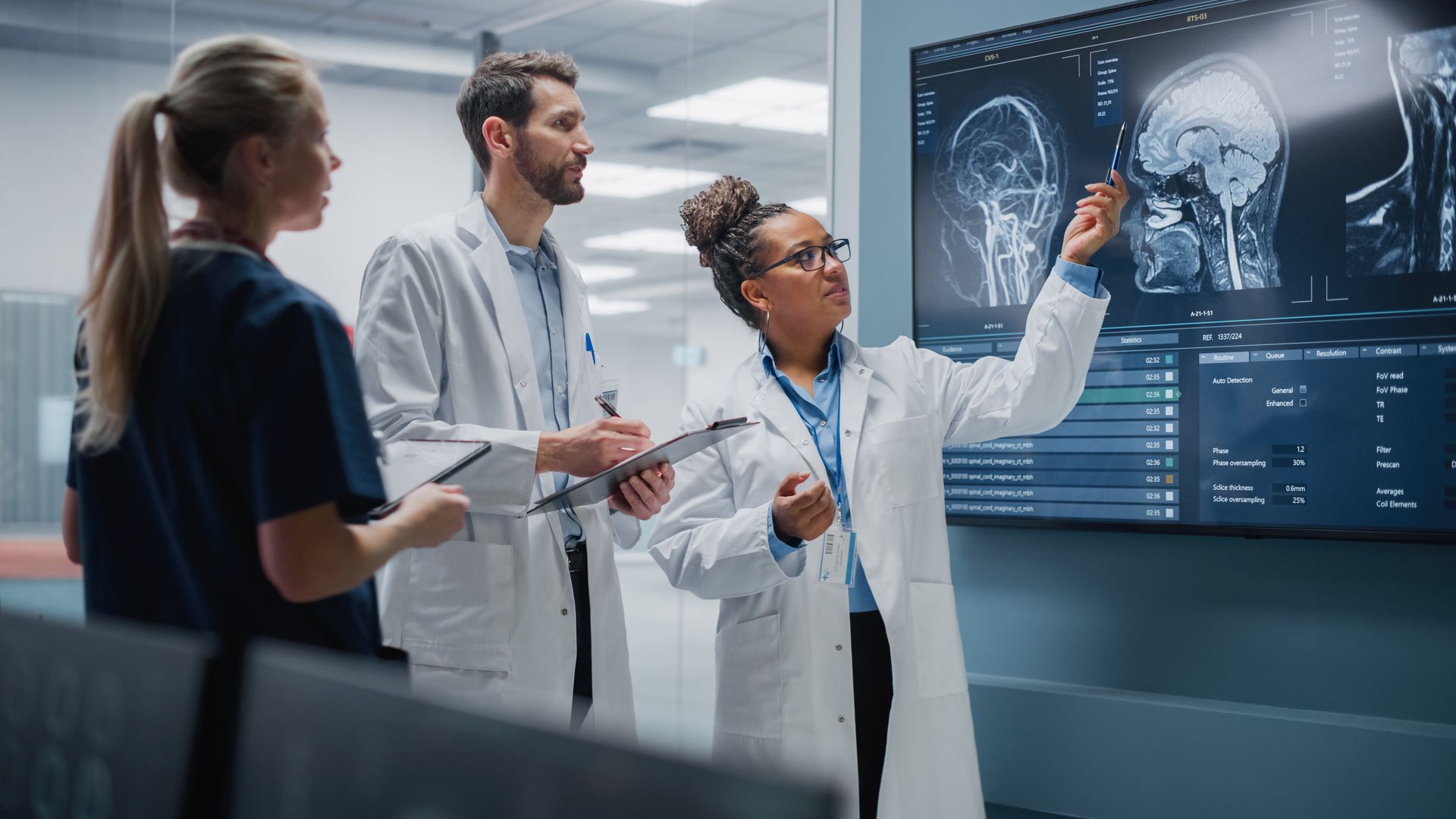 Medical team reviewing brain scans on a large digital display in a modern hospital room
