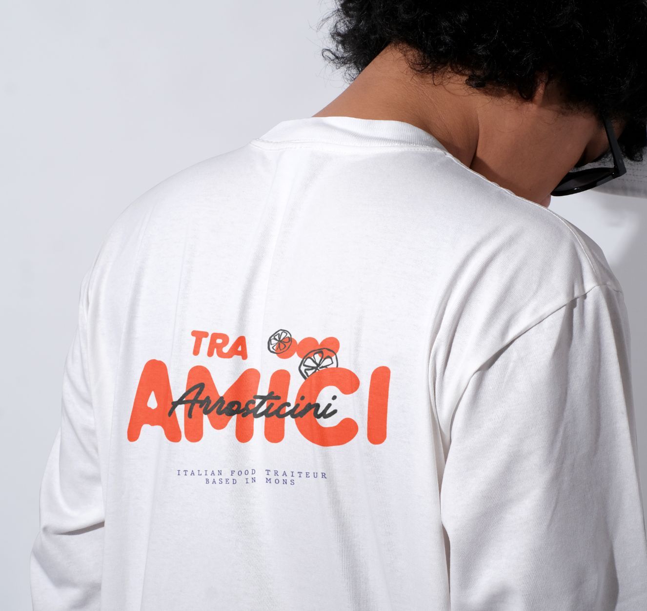 Personne portant une chemise blanche à manches longues avec l'inscription rouge « TRA AMICI Arrosticini » dans le dos.