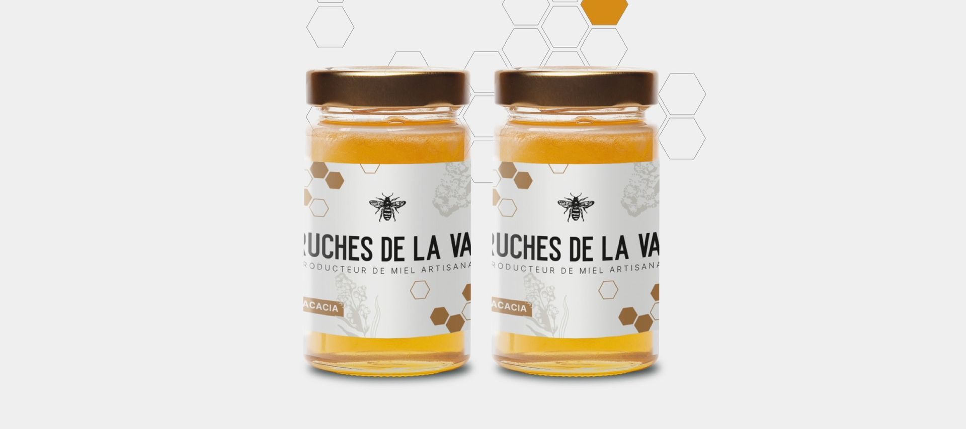 Deux pots de miel en verre avec couvercles bruns et étiquettes blanches.