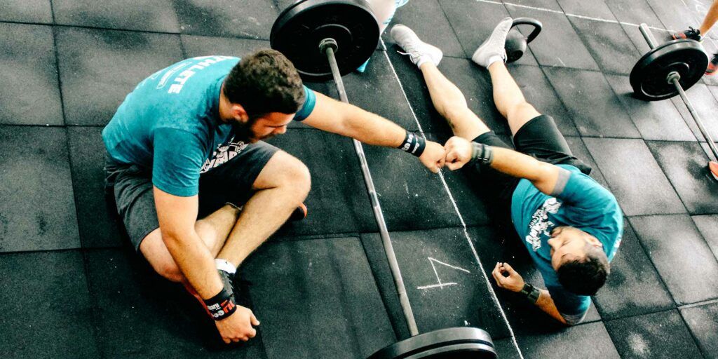 A man is helping another man lift a barbell in Portland, OR's best CrossFit gym.