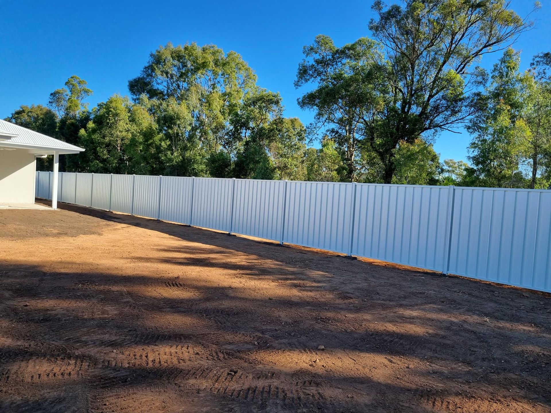 A White Lattice Fence is in Front of a Brick House — RBG Building & Maintenance in Veteran, QLD
