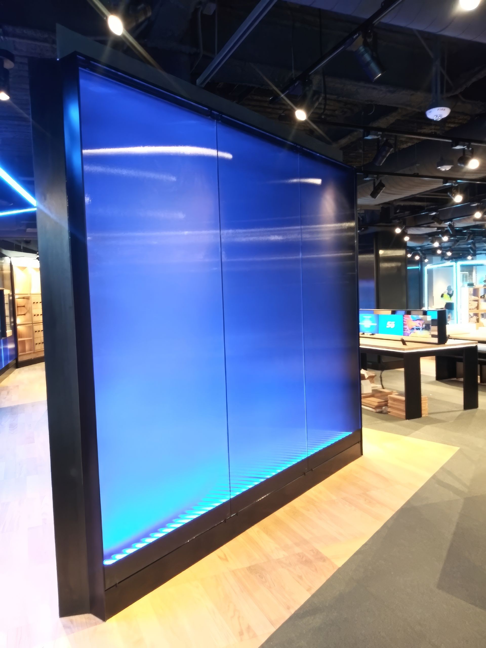 Large blue illuminated display wall in a modern office or showroom interior