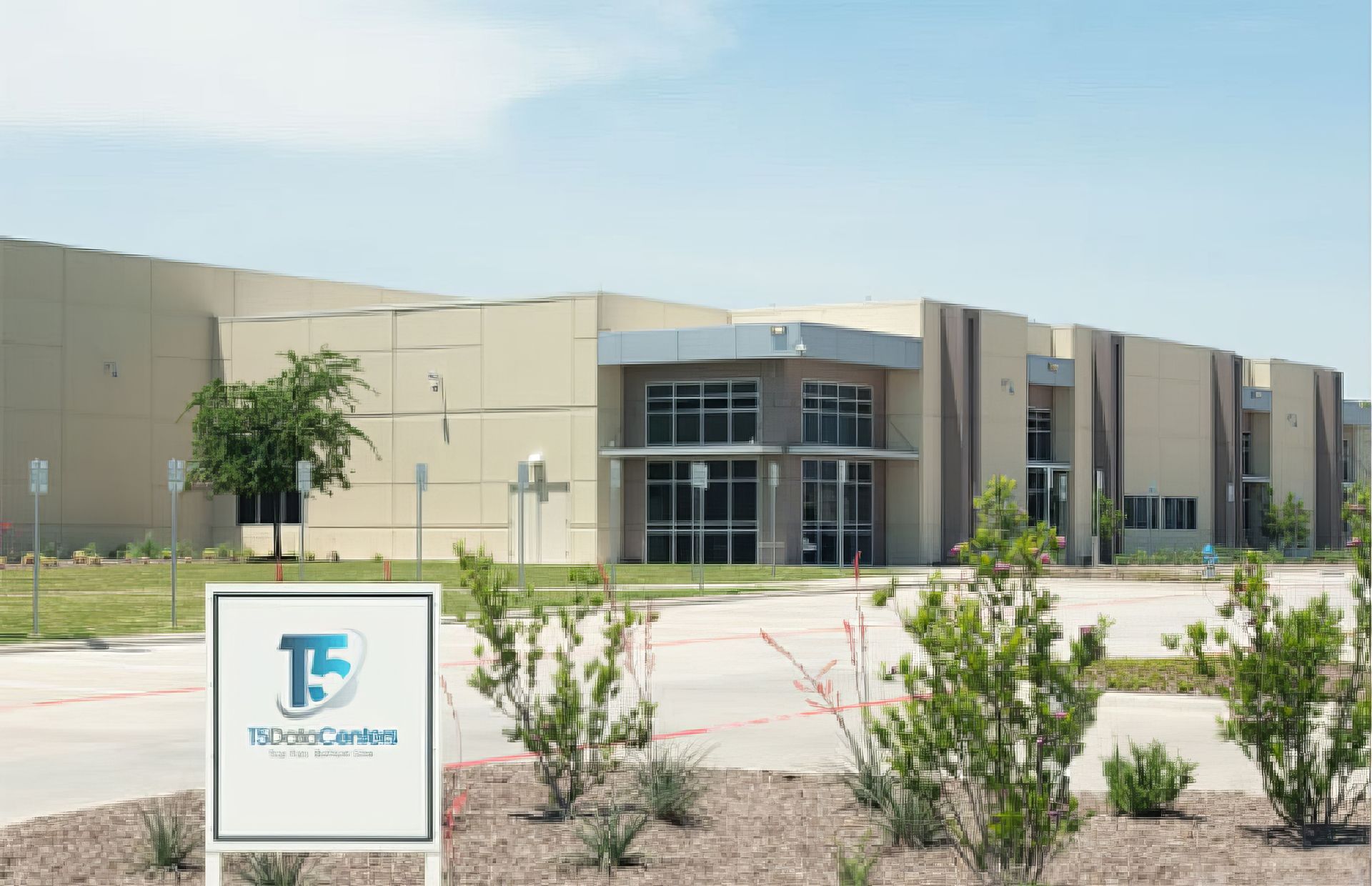 Modern beige building with glass entrance and a sign in front reading 