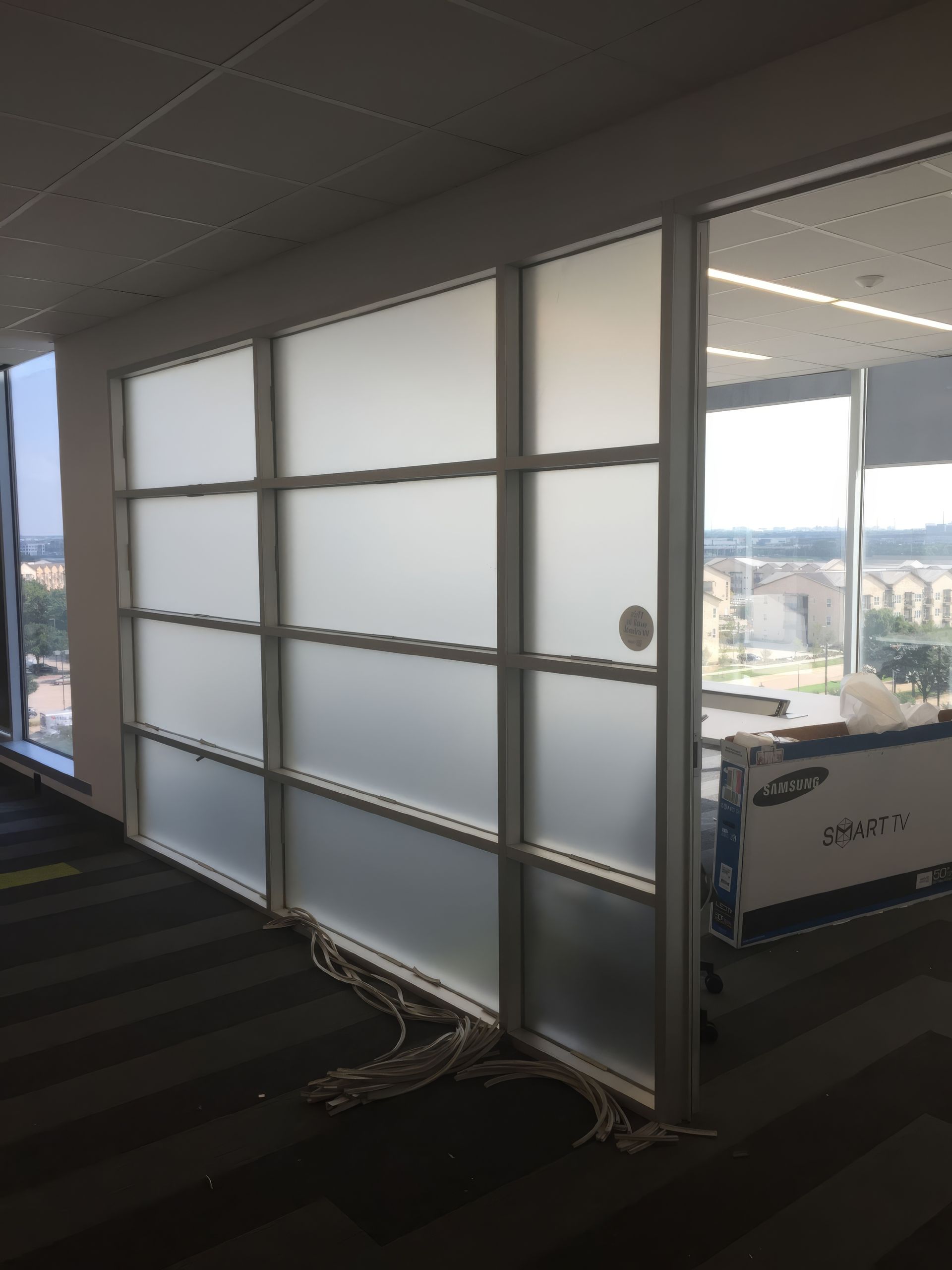 Office corridor with frosted glass wall panels and a view of the city outside