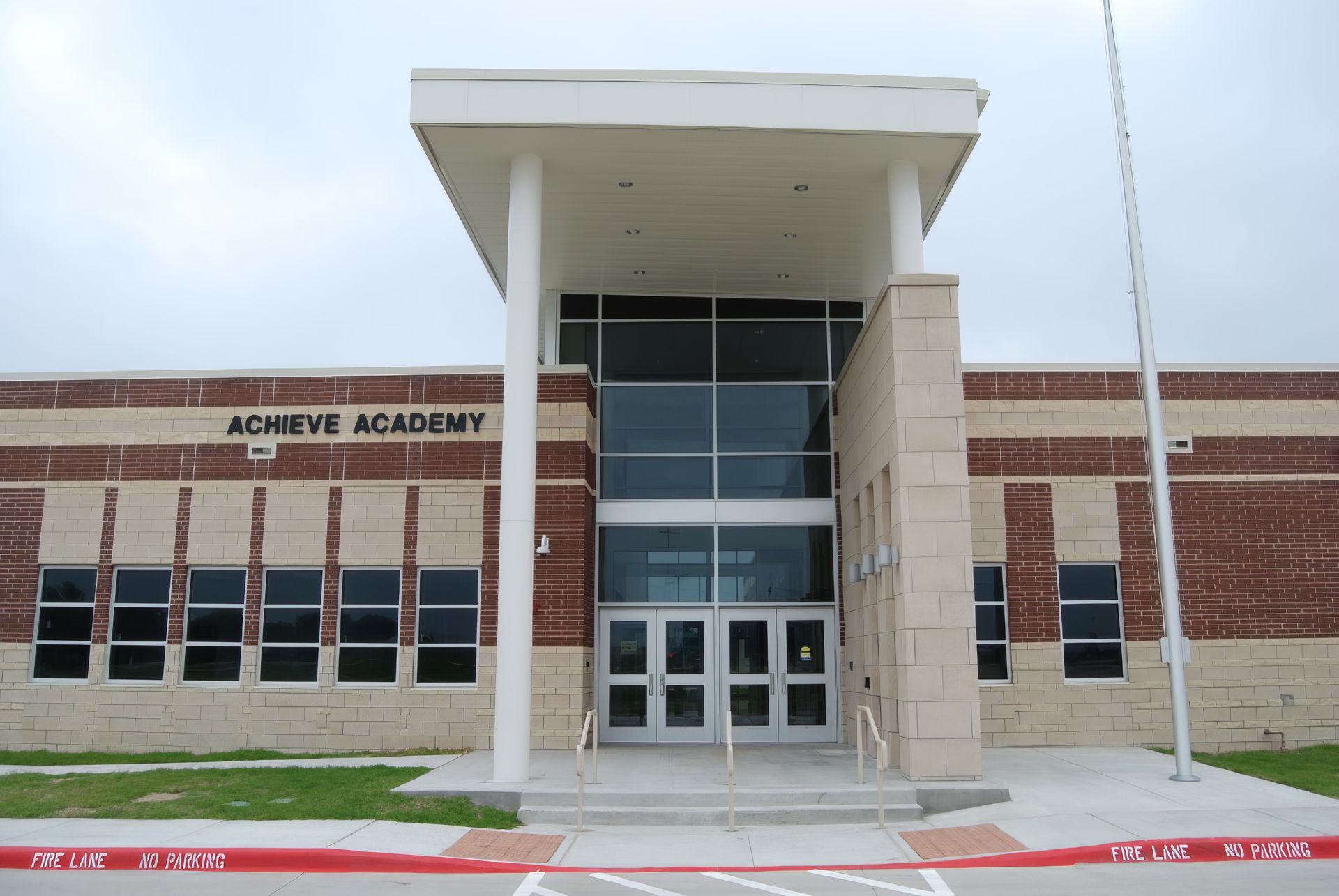 Front entrance of Aomeve Academy, a modern brick school building with a covered glass doorway.