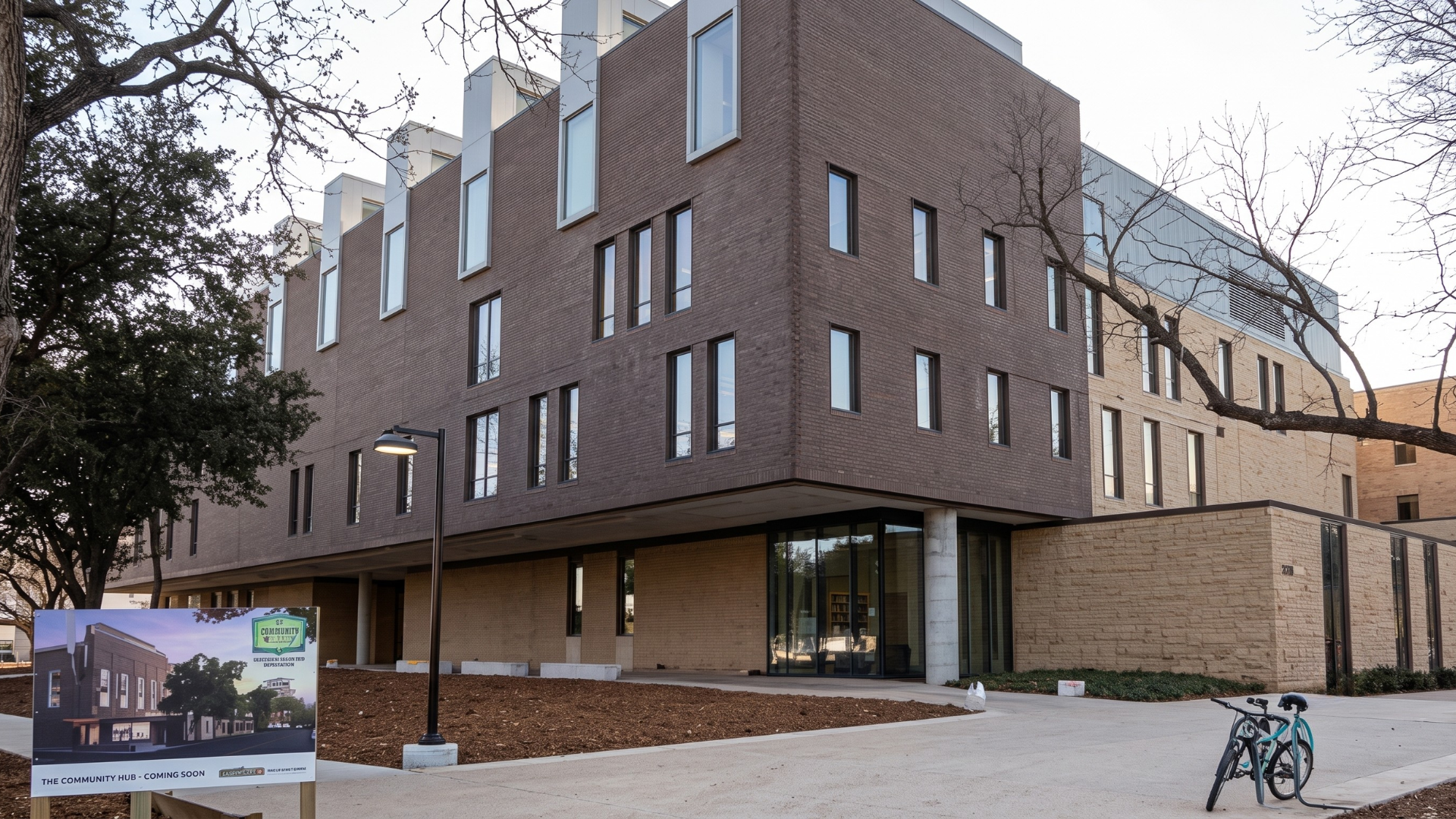Modern brick building with tall narrow windows and a covered entrance at dusk
